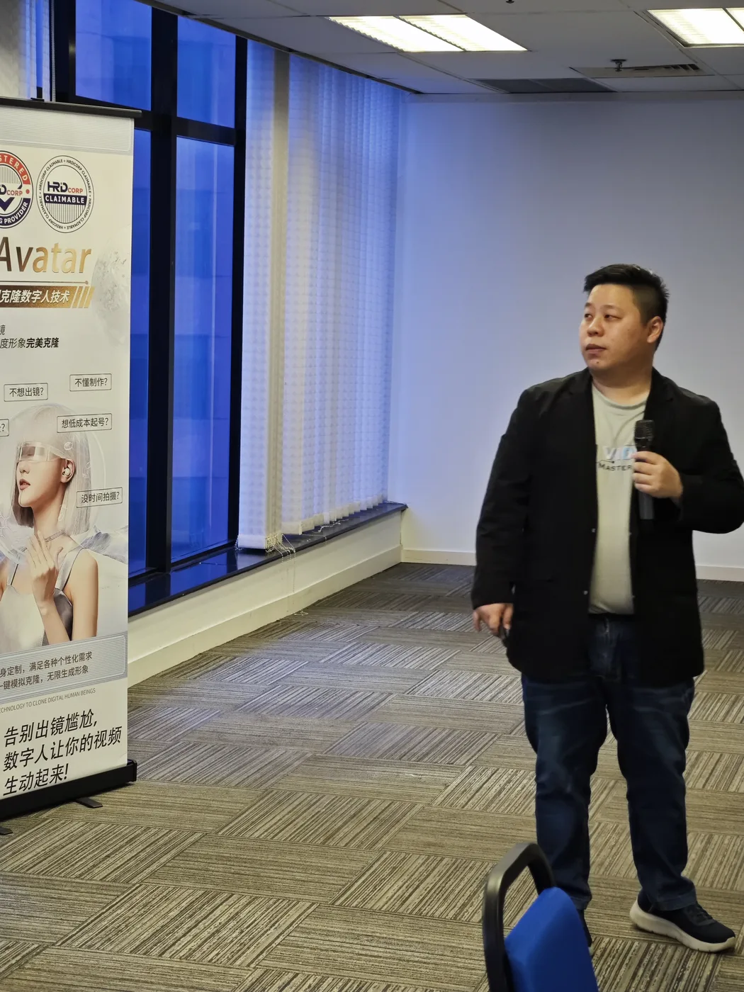 Max Ng 手持麦克风站在数字人横幅旁